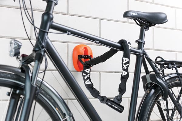 Billedet illustrerer en cykellås i form af en kædelås. På billedet illustreres det hvordan cyklen fastgøres via en kædelås